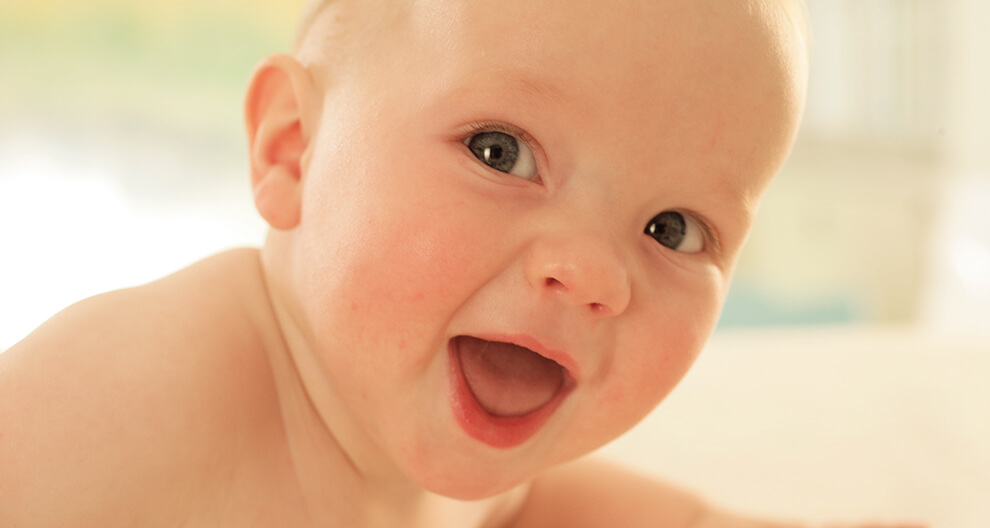 A baby with a wide-open mouth and a curious expression.